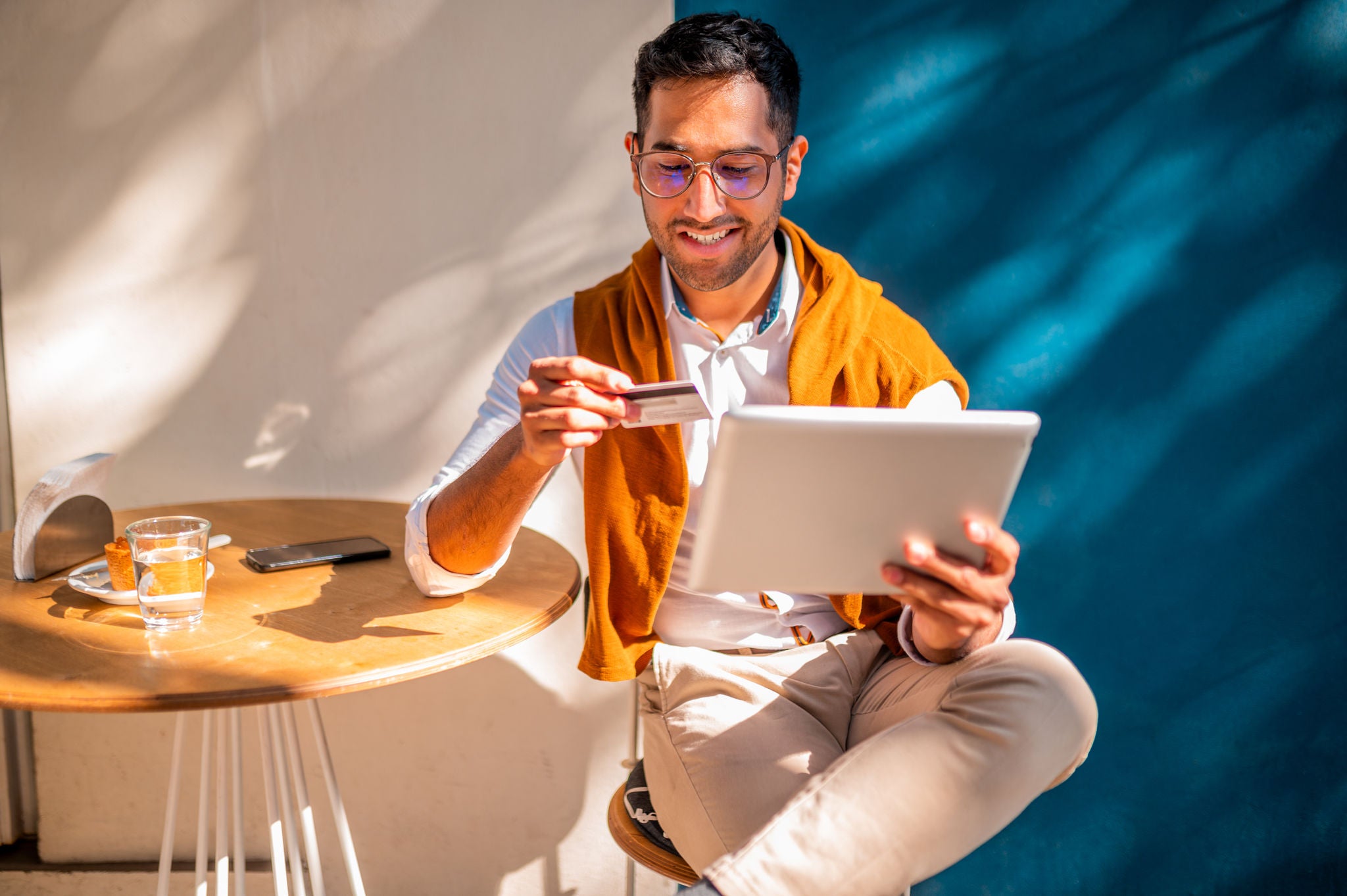 Young man looking at digital tablet using his credit card to pay online